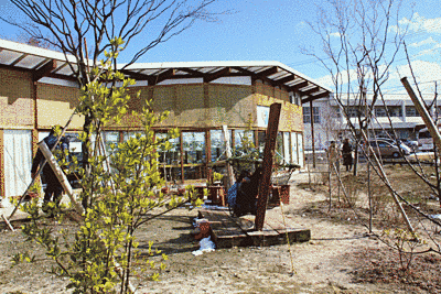 奥には建物が見えます。中央部にはハンモックがあり、周囲には樹木が植えられています。