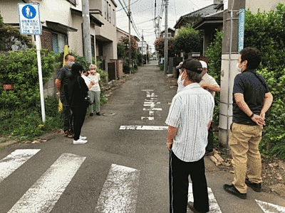 路地で複数の人が向かい合ってお話を伺っています。