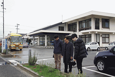 奥に淡路市一宮事務所庁舎が見えます。手前では3人の方が駐車場の花壇を眺めています。