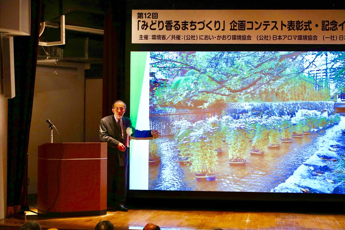 講演の様子です。スクリーンには写真が投影されています。