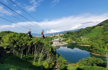 画面中央に大きな池が見えます、池の周りには建物もありますが、基本的には山に囲まれており、山には木々が茂っています。その上をジップラインという遊具で、超えていく事が出来ます。スリルもありそうです。