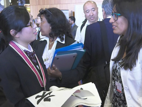 Photo 9: MOYAI Ambassador Ms. Sena Sawai handing out Japanese calligraphy (