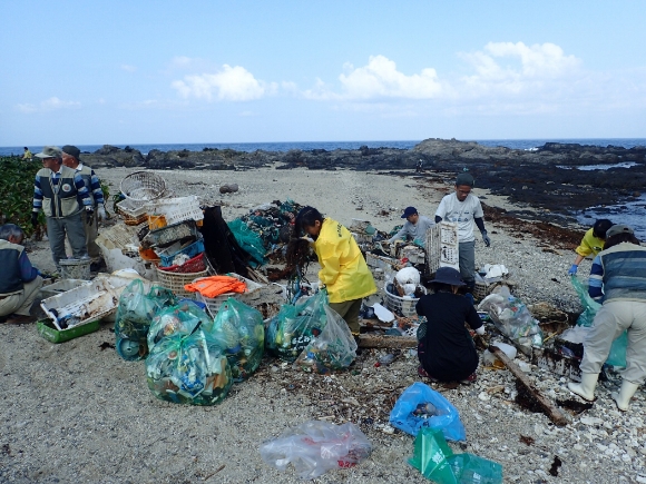 Park volunteers cleaning up trash on the beach. Park volunteers collect the large amounts of garbage drifting in from the sea.