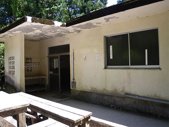 The Shiratani Hut. The building has whitish walls, with a glass door and two windows.