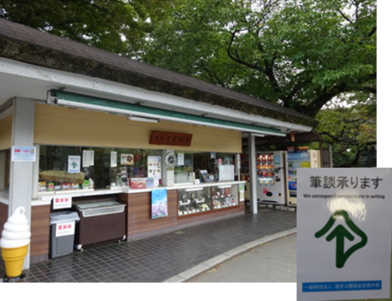 写真：筆談器が配備されている皇居前広場の売店くすのき。こちらの耳マークには筆談承りますのコメントが添えられています。