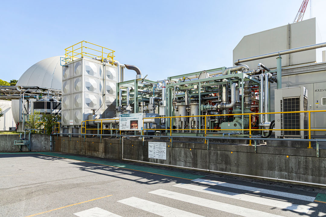 発生したバイオガスはガスホルダー(写真左奥)に貯蔵され、ガスエンジン発電設備(同右)で電気に変換される。
