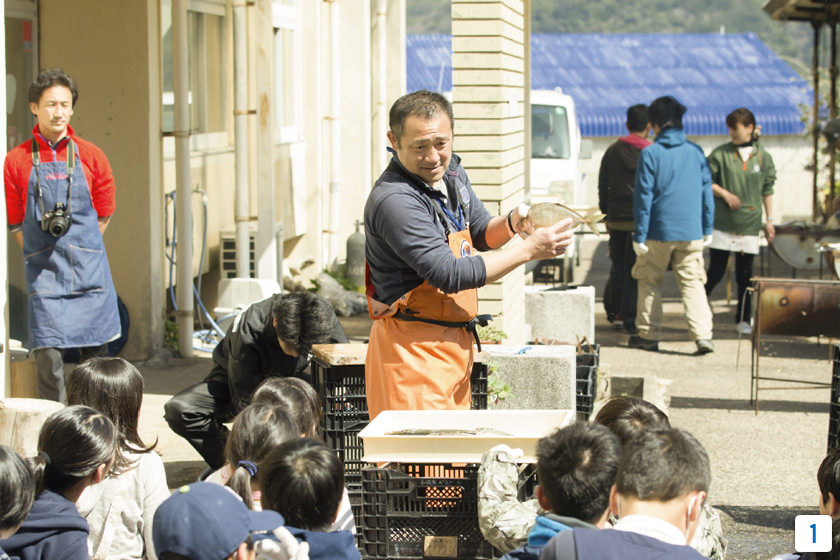 [1]慶應義塾幼稚舎の児童たちが、環境教育の一環で、釣った魚のさばき方についてレクチャーを受ける様子。自分で釣った魚を食べることで、海の恵みを丸ごと実感できる