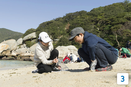 [3]柏島の海岸で「微小貝」を探すこどもたち。微小貝とは、大きさが数mmの、非常に小さな貝のこと。環境のよい場所でないと生息できないが、柏島の浜辺では目にすることができる