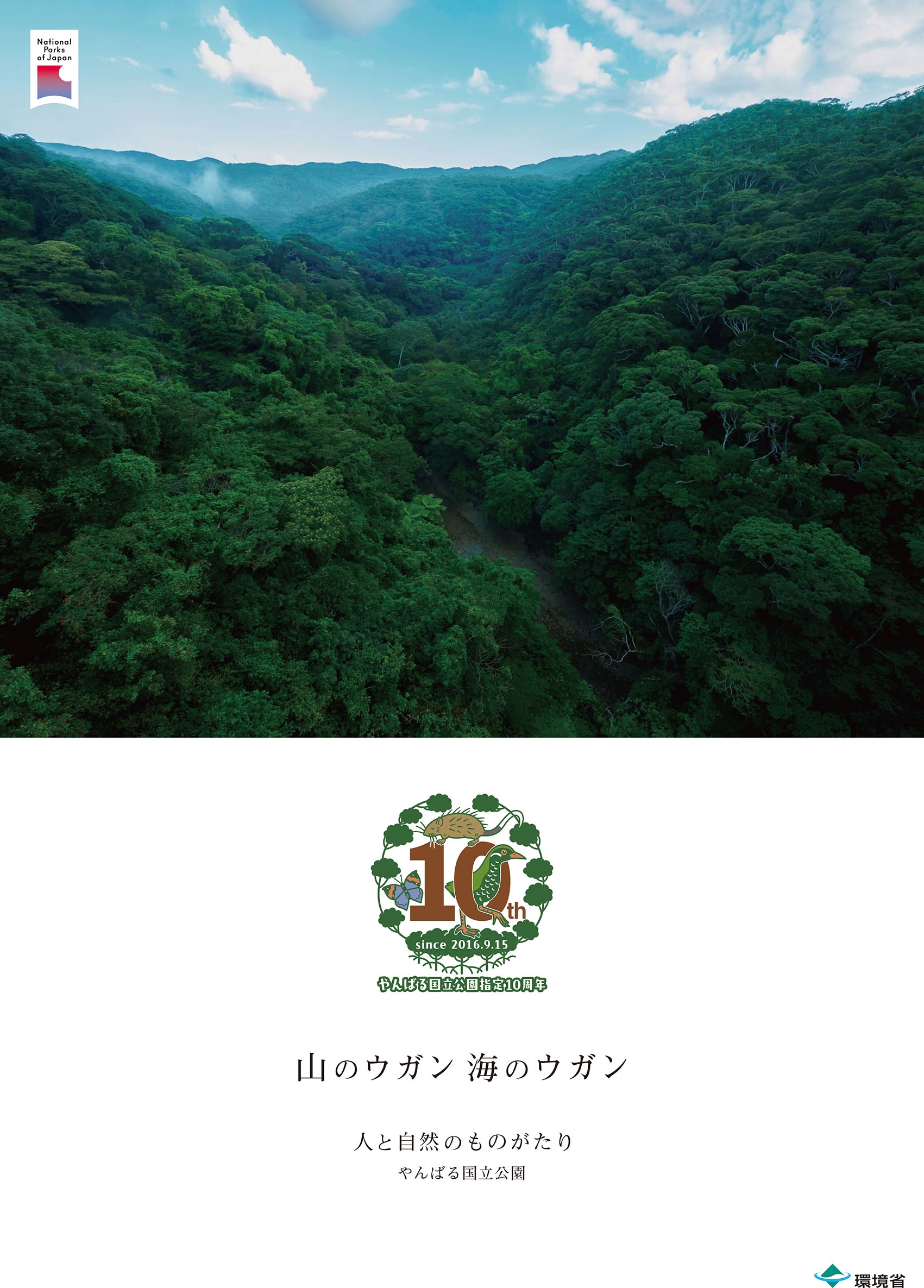 やんばる国立公園の深い森林を見渡す航空写真。中央に国立公園指定10周年記念ロゴ、下部に「山のウガン 海のウガン 人と自然のものがたり やんばる国立公園」の文字が表示されている。