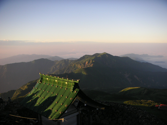 タイトル　日の出直後の白山山頂より奥宮越しの別山