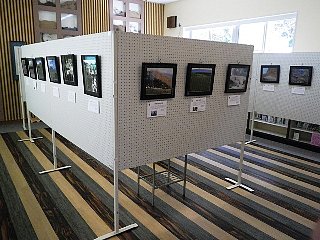 遺産センターで開催された、九州地区アクティブ・レンジャー写真展の様子。白いボードにたくさんの写真が掲示されています。