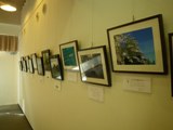 遺産センターで開催された、アクティブ・レンジャー写真展の様子。白い壁に、たくさんの写真が掲示されています。