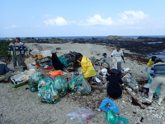 海岸のゴミ掃除をしているパークボランディアの活動風景。砂浜の上に、たくさんの漂着ゴミがパークボランティアの手により集められています。