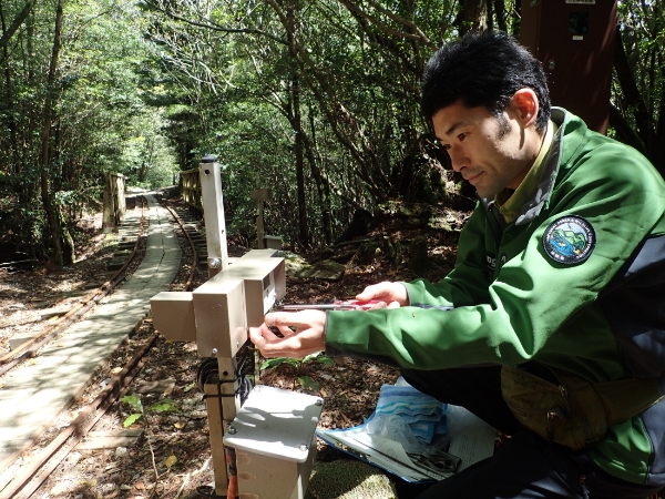 一人のアクティブ・レンジャーが、山岳部の利用動向を把握するために使用する自動観測装置（カウンター）の点検を行っている写真。