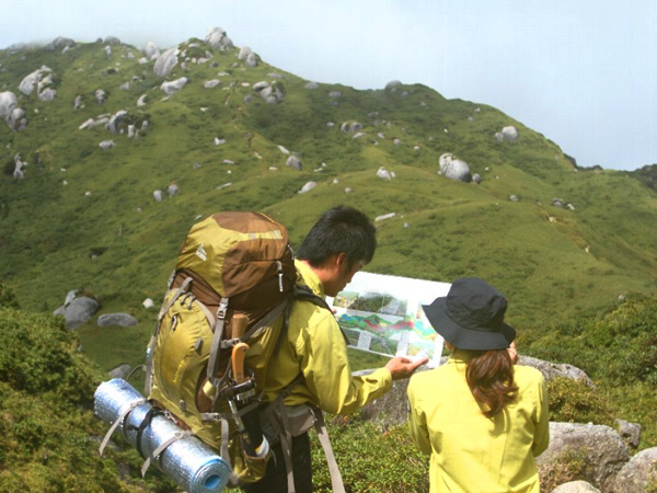 二人のレンジャーが、登山道を巡視している写真。左手にいる男性レンジャーが資料を手に持ち、二人でその資料を見ています。