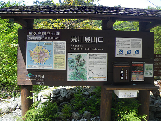 荒川登山口に設置された、案内標識の写真。板面左手には、屋久島国立公園の地図が、中央には荒川登山口から縄文杉までの地図・説明書が貼られています。ボードの右下には、登山届を入れる小さな箱も設置されています。
