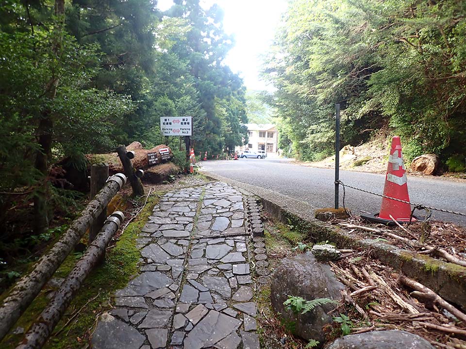 ヤクスギランド出口の写真。写真左手の、やや坂になった石畳の歩道は、右手の道路につながっています。