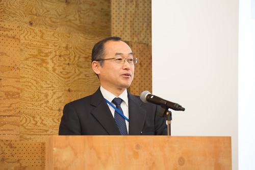 シンポジウムの冒頭で挨拶する環境省の深見正仁・大臣官房審議官の写真。