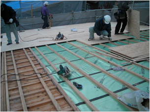 下向きに作業する屋根下地　外断熱材、遮熱シート,通気桟、野地板（2月19日撮影）